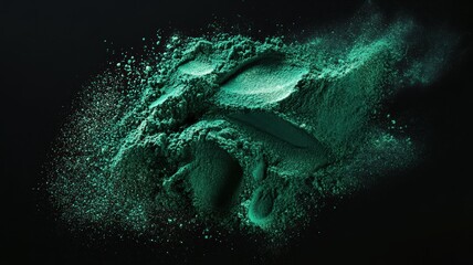 Vivid green spirulina powder scattered and forming dynamic shapes against a dark black background, emphasizing texture and color contrast.