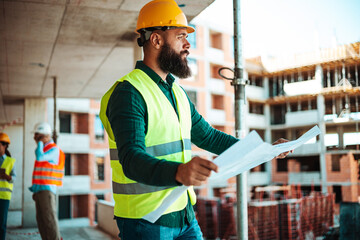 Construction Worker Reviewing Plans at Busy Job Site