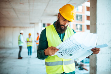 Construction Worker Analyzing Blueprints at Building Site