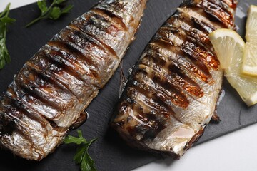 Delicious grilled mackerel, parsley and lemon on white table, closeup