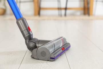 Cleaning floor with cordless vacuum cleaner indoors, closeup. Space for text
