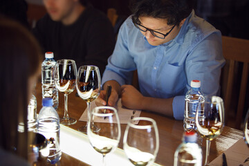 Sommelier Evaluating White Wine Varieties and Scribbling Observations at Tasting Event