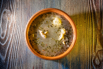 A bowl of hot soup served in a white ceramic bowl on a wooden table