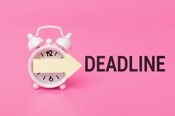 deadline - text written on a pink background, idea for reminders, project timelines and urgent notifications. White alarm clock on pink background with yellow arrow