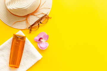 Summer holiday beach background. Female straw hat with sunscreen and sunglasses, top view