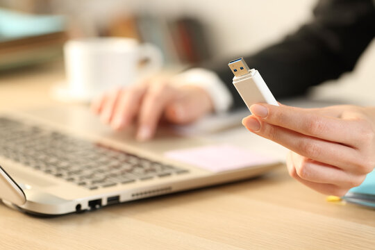 Executive hand holding usb drive using laptop on a desk