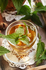 A cup of herbal tea with fresh stinging nettles