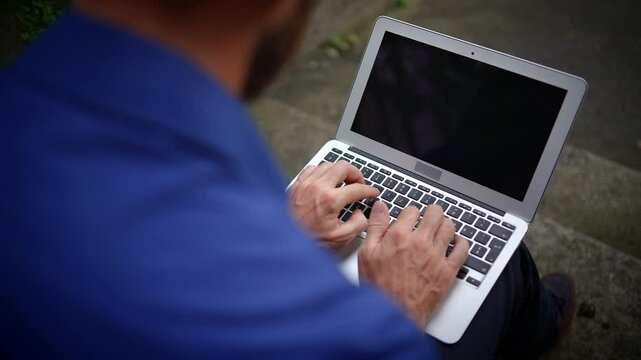 A person is typing away on a laptop in a relaxed outdoor environment, enjoying nature