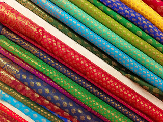Pallet of vivid and colorful Indian fabric, Closeup view of stacked colours saris or sarees in display of Indian retail shop, textile shop.