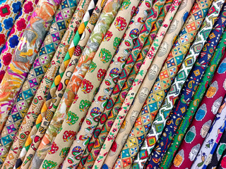Pallet of vivid and colorful Indian fabric, Closeup view of stacked colours saris or sarees in display of Indian retail shop, textile shop.