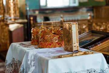 Ornate Golden Crowns and Religious Artifacts on Embroidered Altar Table in Historic Church Interior