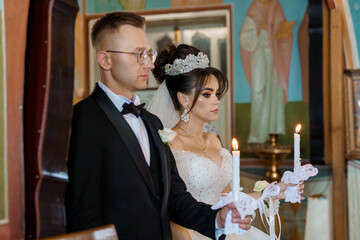 Elegant Orthodox Wedding Ceremony with Bride and Groom Holding Candles in Church