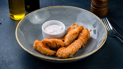Fried chicken nuggets with sauce on a dark background.