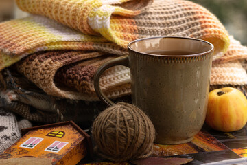 Waiting for autumn to come. A knitted scarf and hot tea on the windowsill create a cozy atmosphere. Autumn mood.