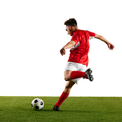 Focused sportsman, dressed in red and white, performing dynamic strike on ball during football training against white studio backdrop. Concept of championship, sport events, final game. Ad