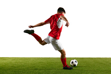 Determined football player in red-white, launching into jump-kick while training against white studio backdrop. Dynamic photo. Concept of championship, sport events, final game. Ad