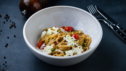 Lunch pasta with eggs, tomatoes and pistachio nuts.