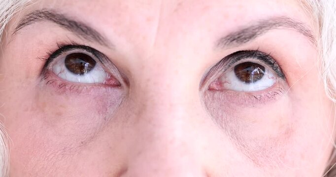 Brown eyes of elderly woman makes relaxing exercise for eyes. Hyperopia myopia astigmatism and glaucoma in retirement