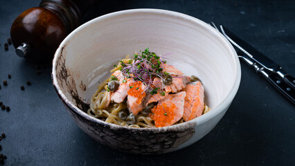 Lunch pasta with salmon, red caviar, capers, sauce and microgreens.