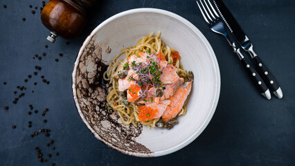 Pasta with salmon, red caviar, capers, sauce and microgreens.