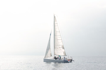 Sailing team adjusting sails on yacht during regatta on calm sea