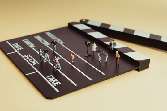 Miniature film crew working on movie set with clapperboard