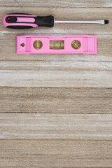 Retro pink screwdriver and level on wood background