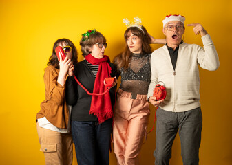 Group of people in festive attire posing with props against a yellow background © C&A