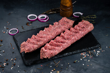 Shish kebab from raw beef minced meat on a dark background.