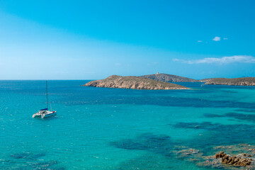 Emerald view of Mediterranean Sea island with boat and tower in the background and blue sky