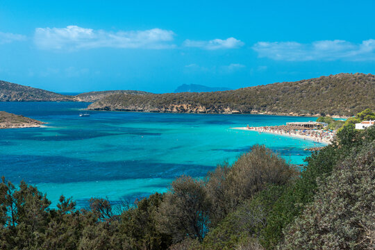 View of emerald sea and  white beach, Boat anchored in the bay in the background - Tuerredda, Sardina