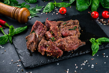 Raw barbecue beef with mustard, spices and onion on a dark background.