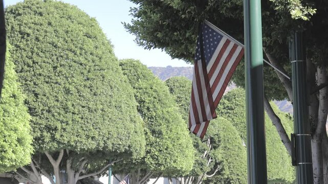 American flag hanging downtown in Glendora, California with gimbal video walking forward.