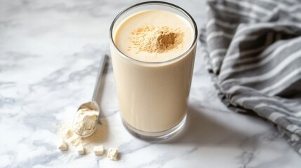 A vanilla protein shake in a clear shaker bottle with a scoop of vanilla protein powder beside it.