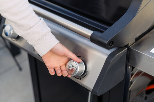Persons hand adjusting knob on stainless steel gas grill