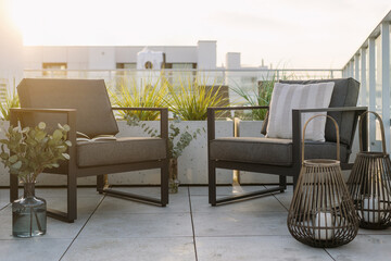 Armchairs and lanterns with candles on terrace with city view on background