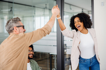 A high-five moment captures the joyful success within a team, as a woman beams with pride and a colleague applauds, showcasing a supportive and uplifting office culture. Value of team achievements