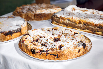Homemade pies, pastries covered with powdered sugar served on white tablecloth, delicious baked desserts assortment, food photography concept