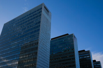 Tall modern office buildings against a clear blue sky in an urban environment during daylight showcasing contemporary architecture and design of glass facades.
