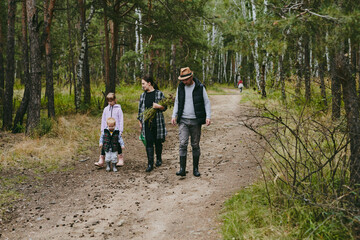 Fototapeta premium Happy family on a walk in the forest picking berries and herbs, traveling along paths and stones mom dad and children