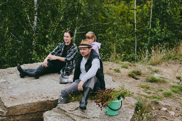 Happy family on a walk in the forest picking berries and herbs, traveling along paths and stones mom dad and children