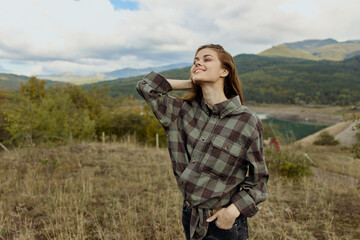 Beautiful Woman Enjoying Serene Nature with Checkered Shirt Standing by Mountain Lake in Travel Destination View