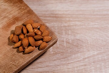 A pile of almonds on a wooden cutting or chopping board