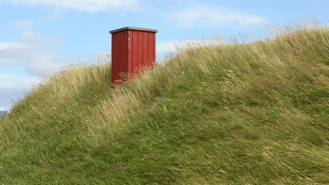 View of a house with typical turf-top grass roof, windy day