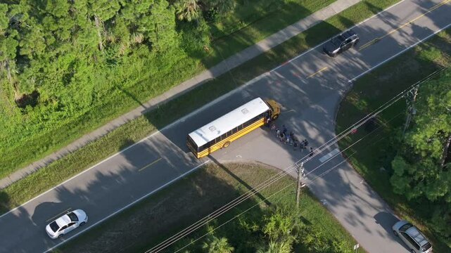 Yellow school bus picking up schoolkids on street bus stop for their lessons in Florida city suburbs. Public transport in the USA