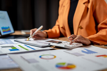 Businesswoman analyzing financial charts and using calculator for business investment