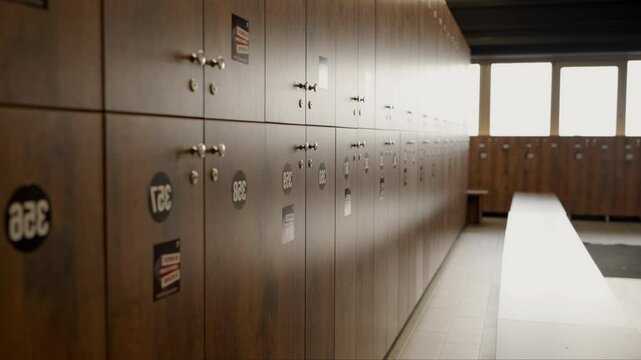 A serene, empty gym locker room featuring rows of closed wooden lockers under soft lighting, creating a calm atmosphere. Empty Gym Locker Room with Rows of Wooden Lockers