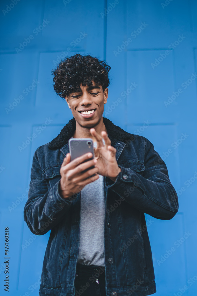 Poster happy hipster guy standing at urban setting and writing email text for sending message to best frien