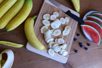 Banany pokrojone w plasterki na drewnianej desce © Monika