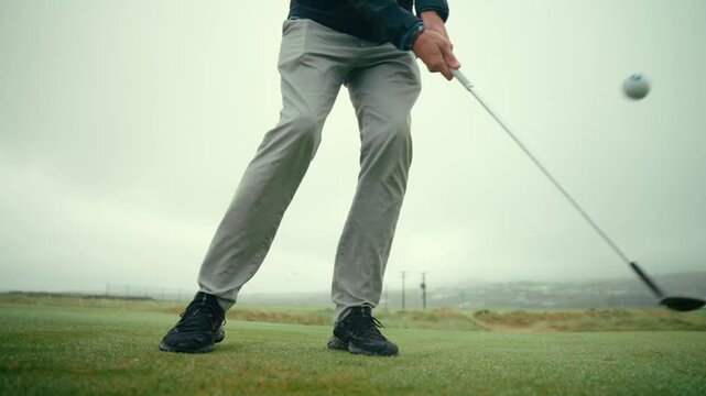 Close up of male golfer using wedge to hit chip shot onto green on Ireland links golf course in slow motion